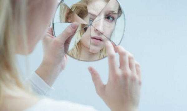 djevojka se gleda u razbijeno ogledalo 